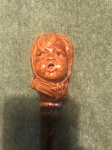 Bastone con pomolo in legno raffigurante testa di bambino che piange.