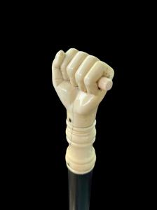 Stock mit Elfenbein-Knauf in Form einer Hand, die ein Siegel hält.