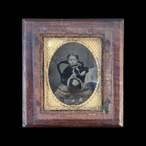 Daguerreotype in a wooden frame with a figure of a child.