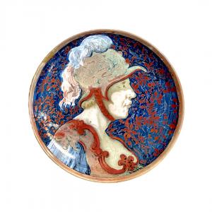 Piatto in maiolica a lustro metallico raffigurante profilo di soldato con elmo e decori vegetali stilizzati.Manifattura Ginori.