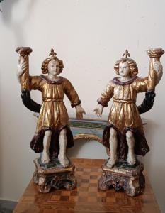Antica coppia di angeli reggicandela antichi, realizzati in legno intagliato, laccato e dorato