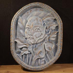 Scultura bassorilievo, volto stilizzato con fiori, XX secolo