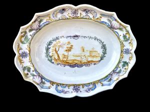 Oval plate with lobed edge, decorated with vegetal and rocaille motifs. Gallant scene in the center.