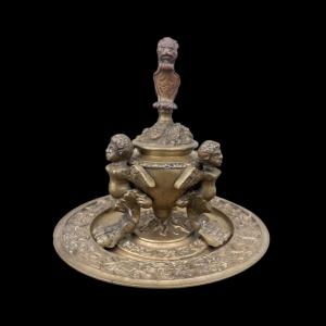 Bronze inkwell with three feet, harpies, lion, putti, vegetal motifs and characters. Italy.