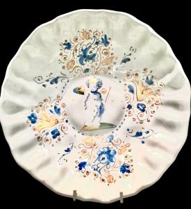 Compendiary maiolica crespina with ribbed rim decorated with vegetal motifs and a cherub. Faenza.