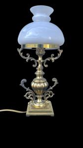 Lampada in ottone con corpo rastremato e bracci laterali rocaille.Cappello in vetro lattimo.