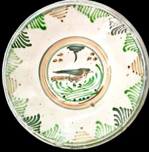 Majolica plate with stylized plant motifs on the rim and a small bird in the center. Montelupo.