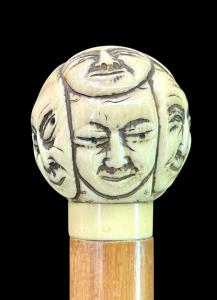 Stock mit rundem elfenbeinfarbenem Knauf, der mit Masken der Commedia dell'arte geschnitzt ist. Japan.