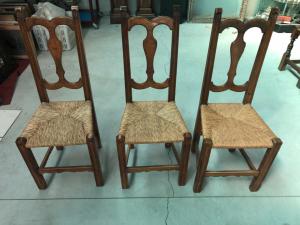 Five blond walnut chairs with straw-covered seats.