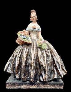Figura femminile con cesto di fiori.Manifattura di Guido Cacciapuoti.Milano.