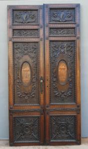 PTI754 - Porta in noce, due battenti scolpiti con mascheroni e decori fogliacei, epoca '800, misure cm L 106 x H 211