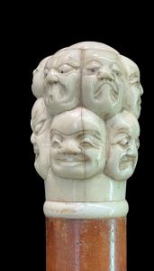 Stock mit Elfenbeinknopf, geschnitzt mit Masken der Commedia dell'arte. Japan.
