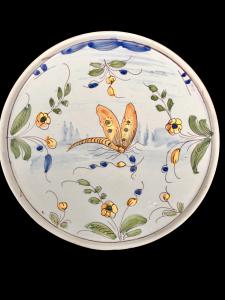 Berettino-ground majolica serving plate with butterfly and stylized plant motifs. Pavia.