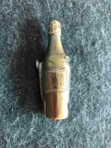 Brass matchbox in the shape of a champagne bottle (Veuve Cliquot) with a cigar cutter. France.