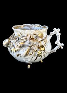 Porcelain mustache cup with raised fruit decoration.