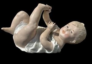 Babyfigur „Piano Baby“ aus polychromem Bisquitporzellan. Manufaktur Heubach, Deutschland.