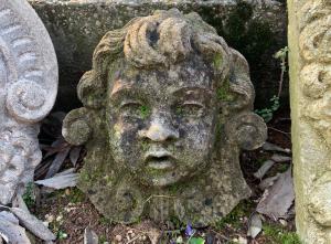 Mascherone in pietra a forma di putto