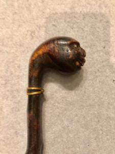 Einteiliger, ebonisierter Stock aus Obstholz mit Knauf in Form eines grotesken Kopfes.