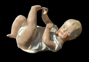 Porzellanfigur eines Babys 'Piano Baby' aus polychromem Bisquitporzellan. Manufaktur Heubach, Deutschland.