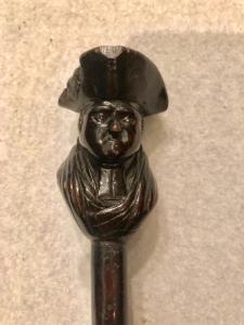 Stock mit Ebenholzknauf, der eine Figur mit Hut darstellt.