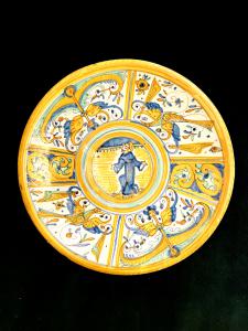 Piatto-tagliere in maiolica con decoro  a quartieri a raffaellesche e motivi vegetali rocaille.tondo centrale con figura di Santo.Manifattura di Deruta.