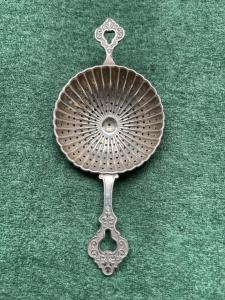 Colino da the in argento baccellato con motivi vegetali stilizzati.Germania.