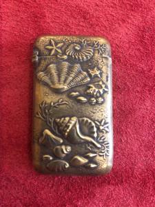 Brass matchbox depicting shells and marine fauna and flora.