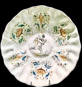 Wavy-edged majolica basin with a compendiario decoration of a putto and stylized floral motifs by Bottega Vicchi, Faenza.