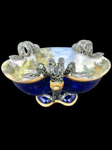 Centro de mesa trilobado em cerâmica policromada com decoração histórica e alças em forma de cobra. Ginori