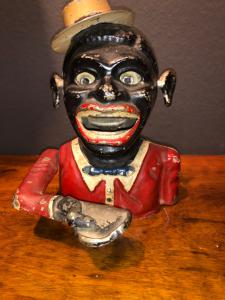 Antimony piggy bank depicting a dark-skinned man with a hat.