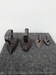 Four solid iron irons of different sizes.