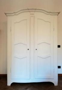 Guarda-roupa branco com 2 portas e moldura superior ondulada.
