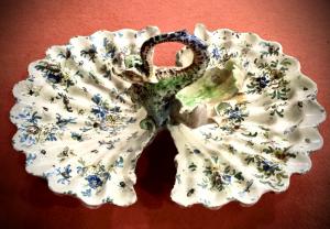 Centro de mesa em faiança com a forma de uma concha bivalve com pega em forma de dragão e decoração com flores e insetos. Angelo Minghetti, Bolonha.