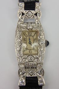 Deco evening watch, in white gold with brilliant-cut and rose-cut diamonds, with a shaped movement marked "Longines" and a cabochon sapphire on the crown