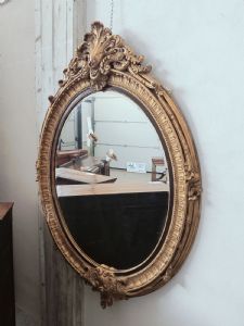 Grande specchiera ovale in legno dorato con cimasa con ricciolo