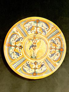 Piatto-tagliere in maiolica con decoro a quartieri a raffaellesche’.Tondo centrale con figura di Cristo in croce.Manifattura di Deruta.