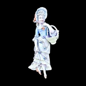 Wandapplike-Skulptur aus Biskuitporzellan, die eine Dame mit Hut und Korb darstellt. Deutschland.