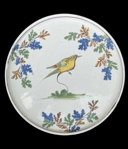 Piatto alzata-tagliere in maiolica con decoro a uccellino e motivi vegetali.Manifattura di Pavia.