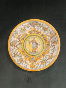 Piatto-tagliere in maiolica con decoro a quartieri a raffaellesche.Tondo centrale con figura di Santa.Manifattura di Deruta.