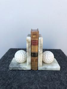 Coppia di fermalibri in alabastro raffiguranti palline da golf.