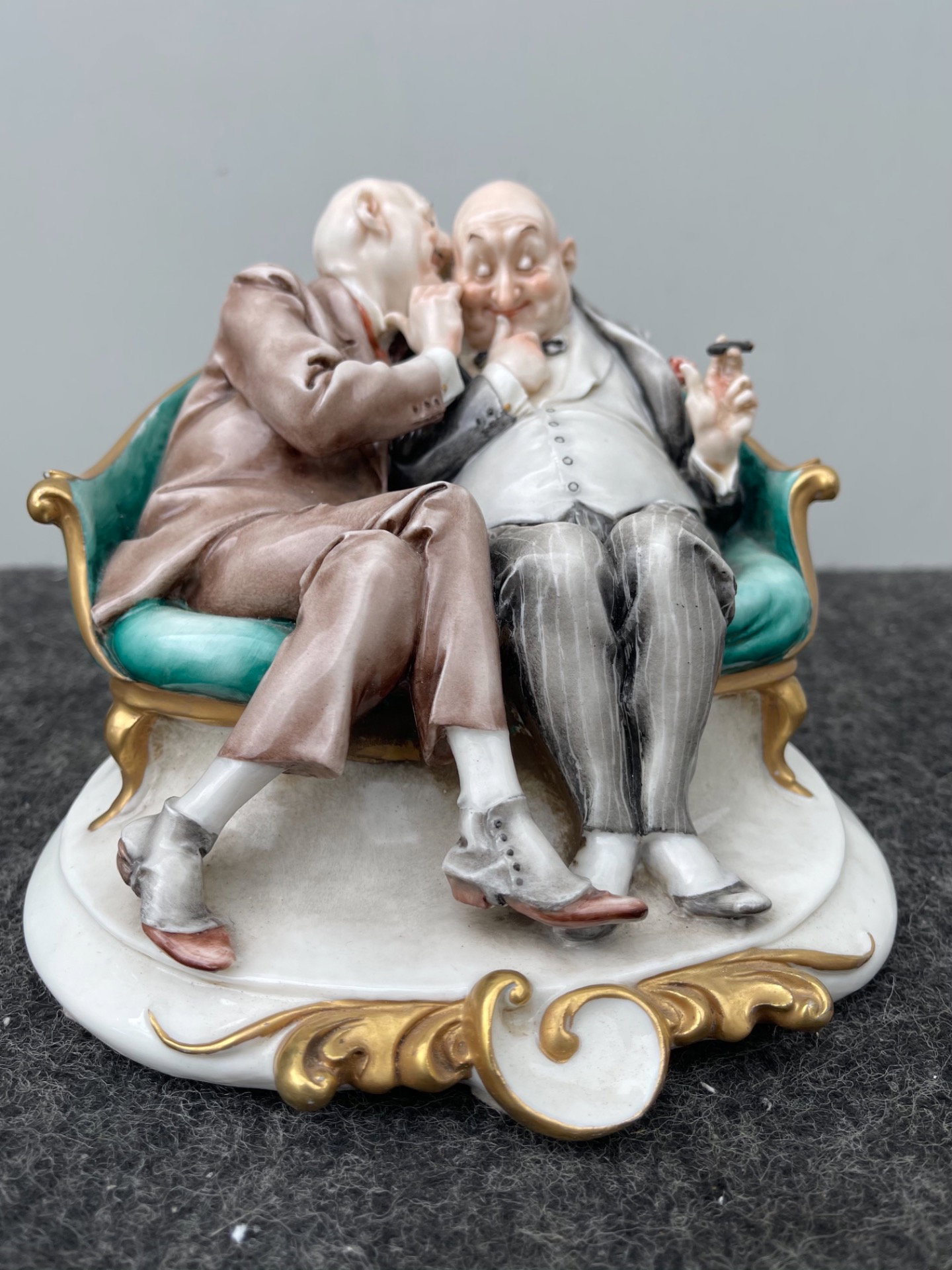 Scultura in porcellana caricaturale raffigurante coppia di amici che si parlano nell’orecchio.Giuseppe Cappe’.