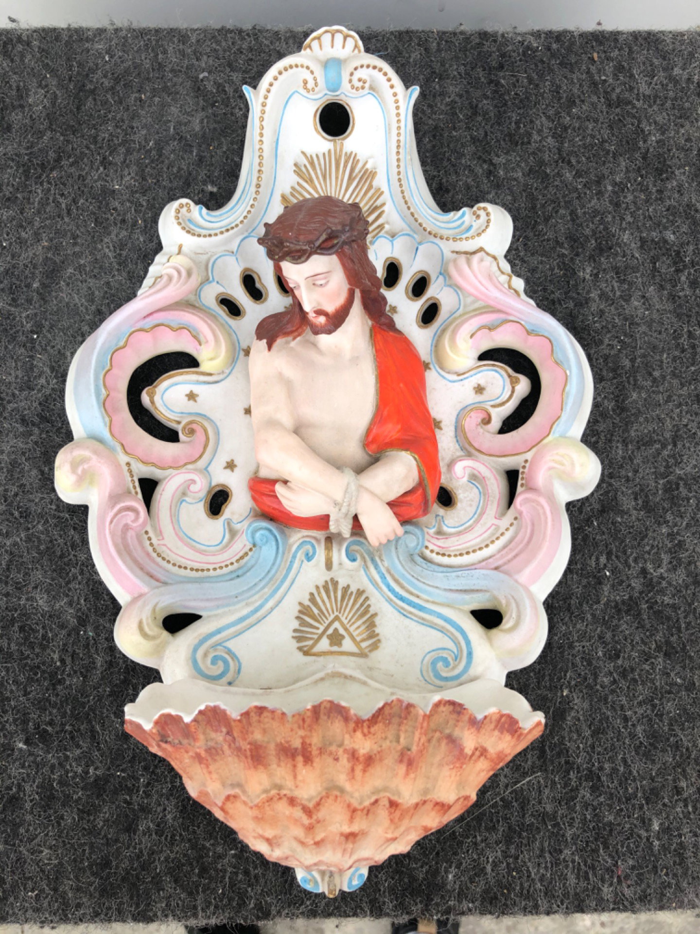 Bénitier en porcelaine biscuit ajourée avec motifs rocaille et figure à mi-corps du Christ lié.