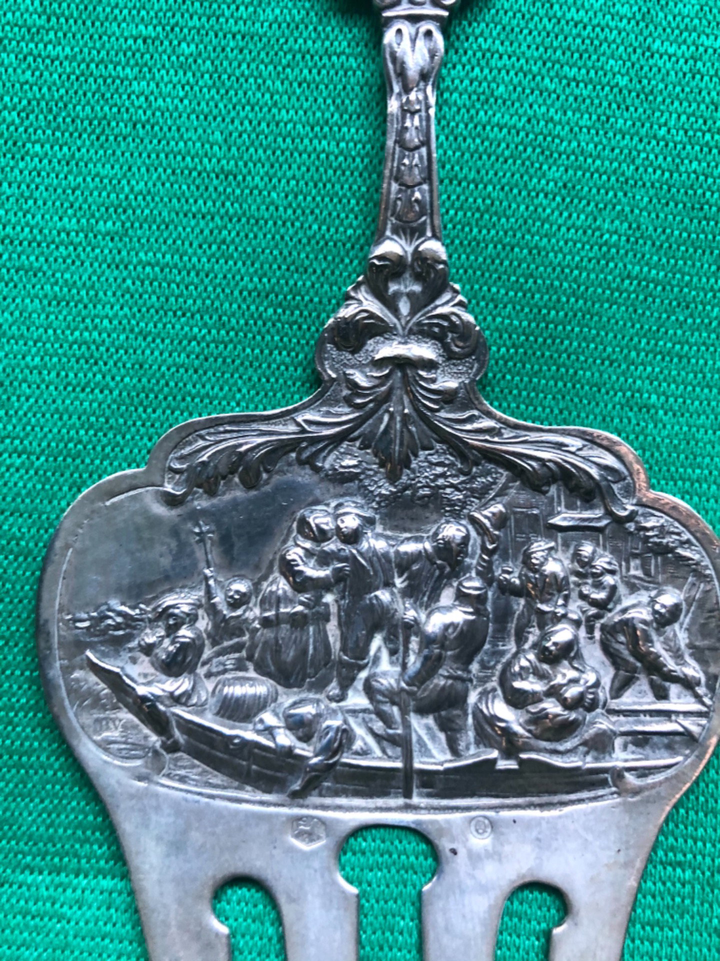 Embossed silver fork with figures on a boat, masks, and stylized floral motifs. Holland 1860.