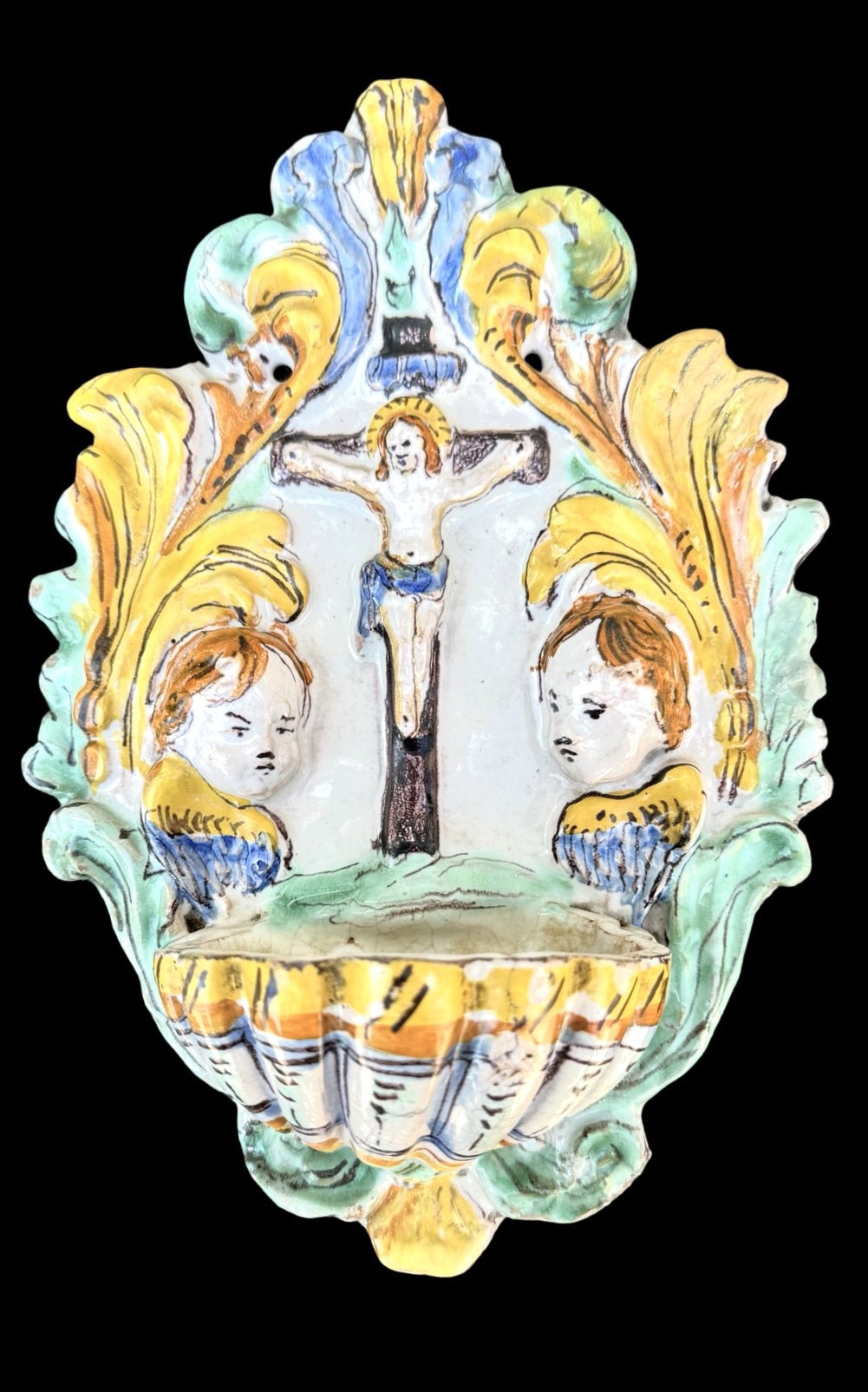 Acquasantiera en mayólica polícroma con figura de Cristo, querubines y volutas vegetales. San Quirico d’Orcia.