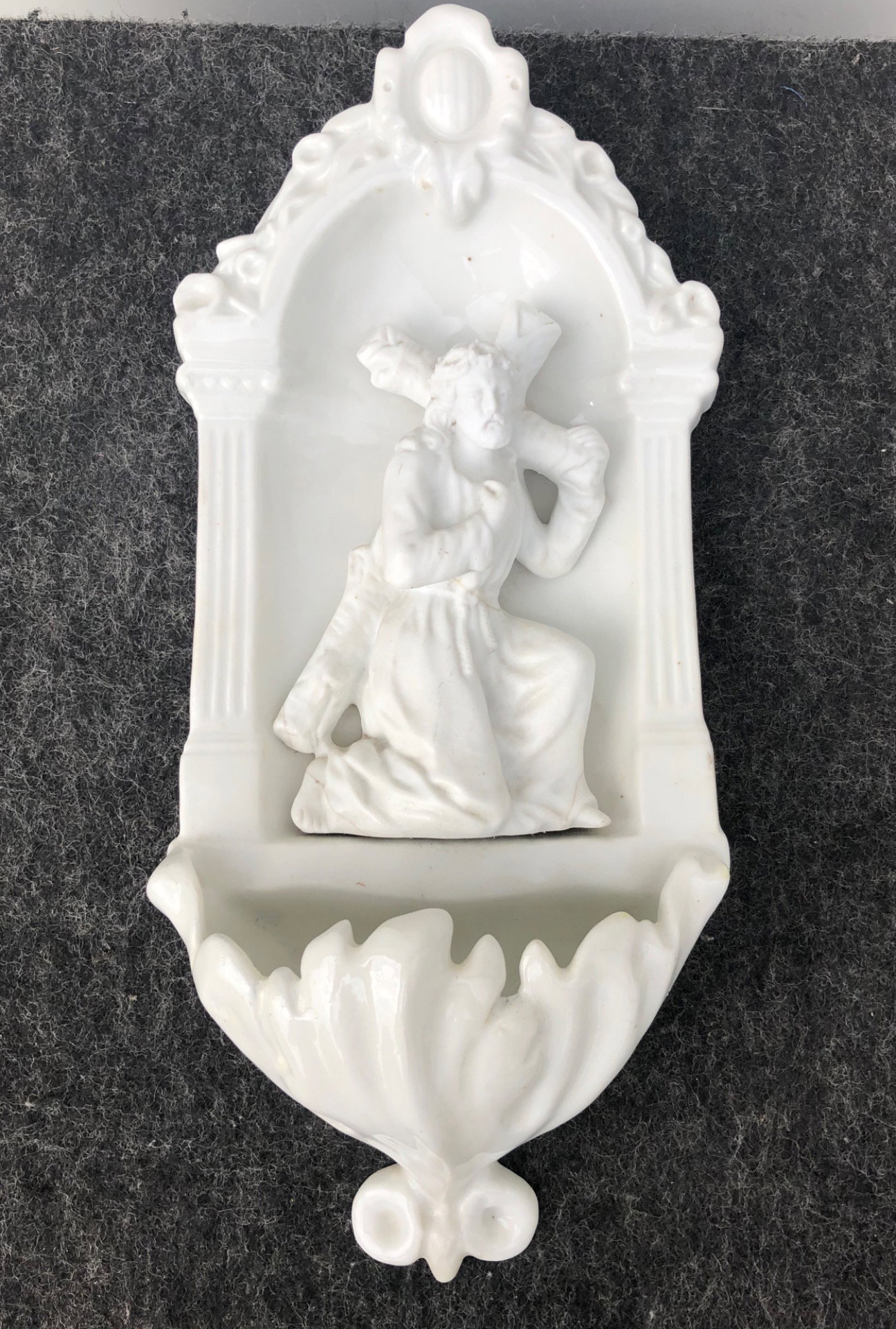 Bénitier blanc avec scène de Jésus portant la croix en biscuit.