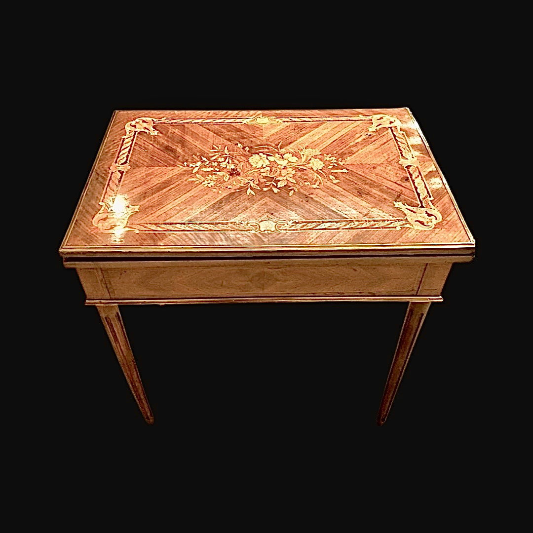 Table de jeu en noyer avec incrustations. Le plateau est coulissant et rabattable et présente à l'intérieur un échiquier pour les échecs, les dames et le backgammon. Provenance: France.