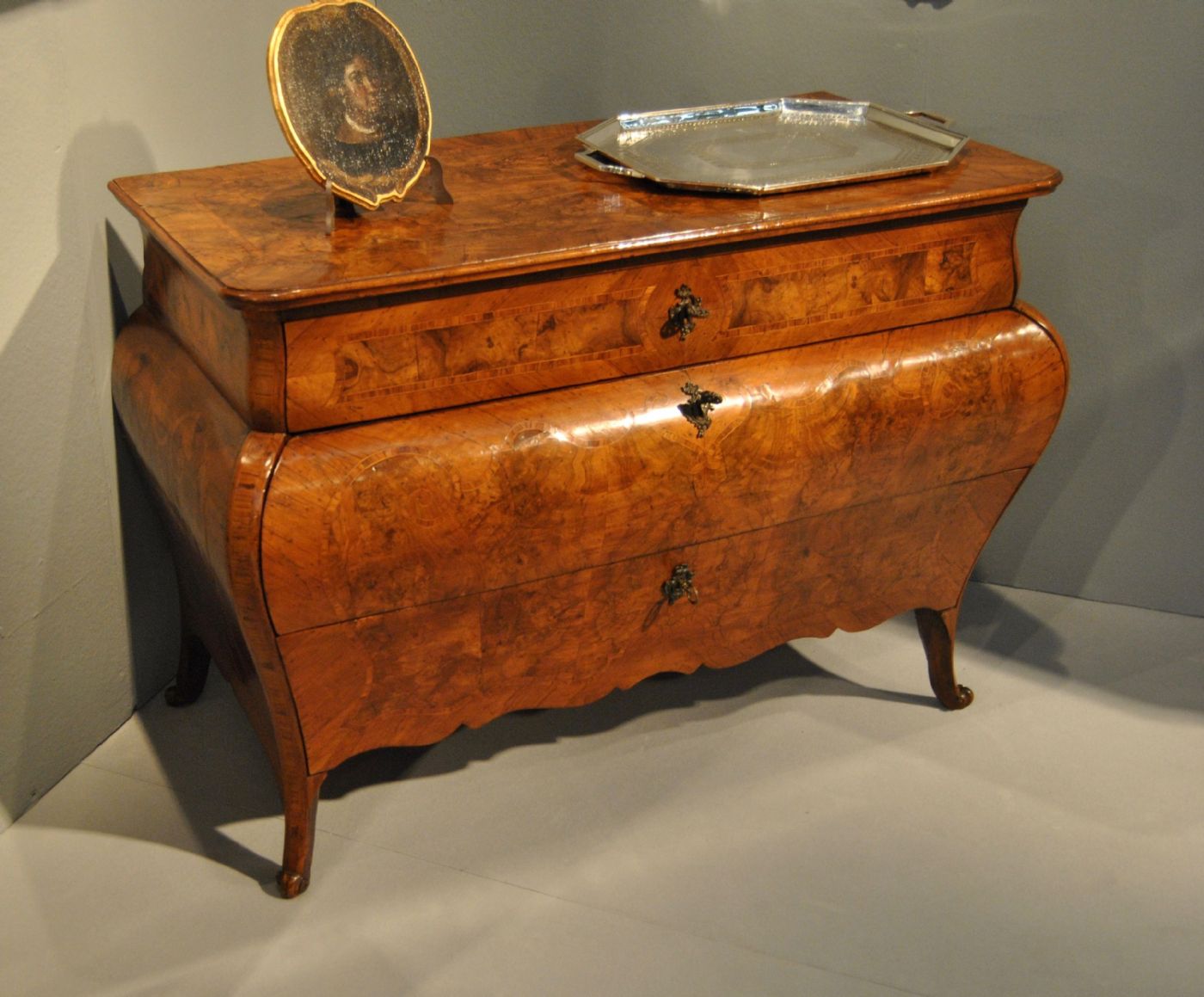Commode bombée en loupe de noyer avec incrustations en bois de rose, production lombarde du XVIIIe siècle. Dimensions : 130 x 60 x 90 cm.