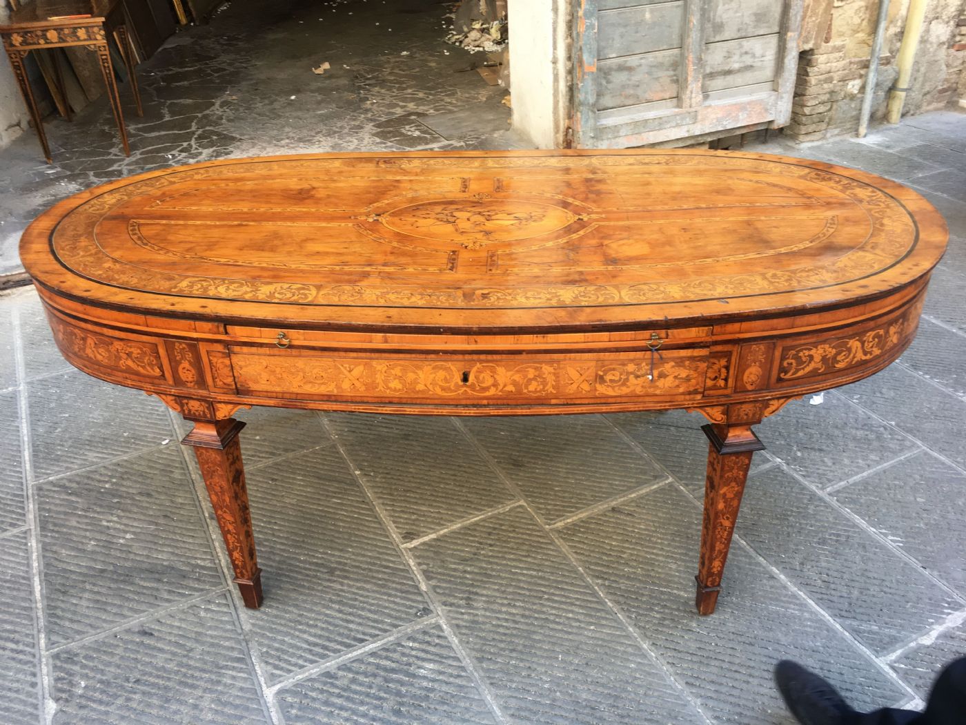 Fabulosa y rarísima mesa "Bottega Maggiolini" finamente incrustada con varias maderas, con cajones y estantes. Cm 200x100