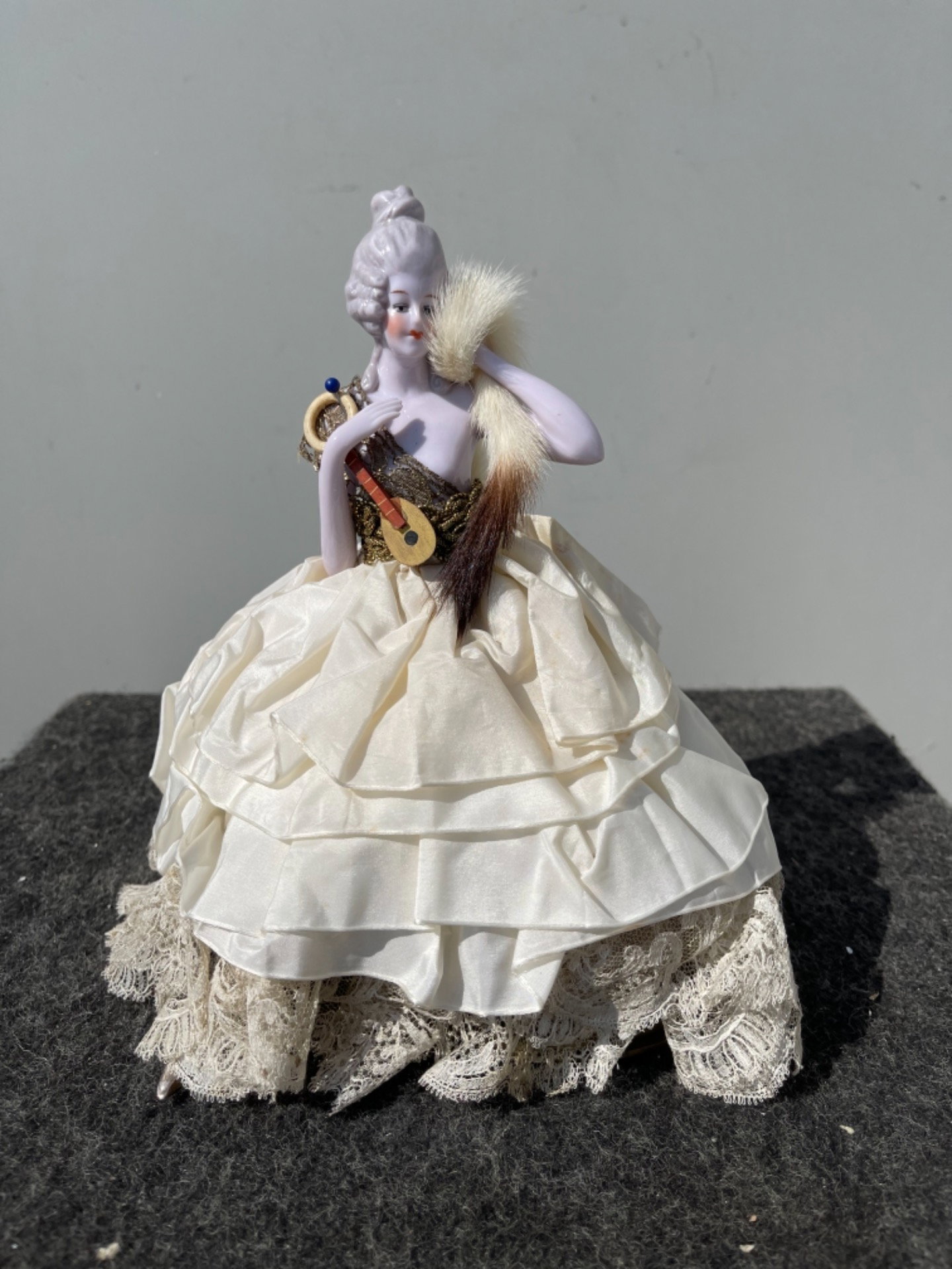 Puderdose 'Half Doll' aus Porzellan mit Dame mit Mandoline. Porzellanbeine. Frankreich oder Deutschland.
