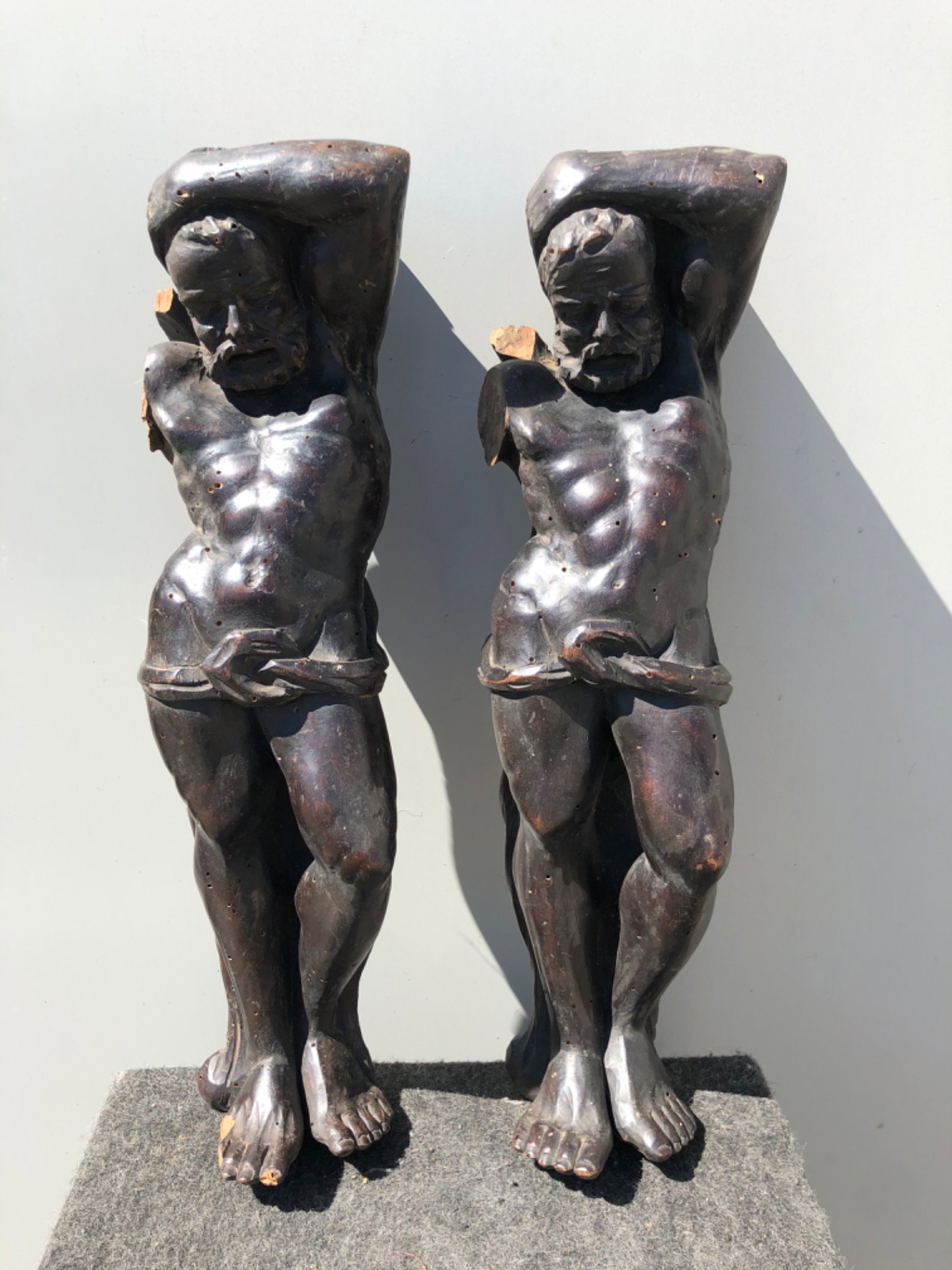 Coppia di fregi-sculture in legno di noce con figure maschili.